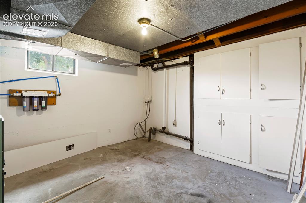 Image 32 of 36: Utility room featuring painted concrete flooring, white walls, and exposed
