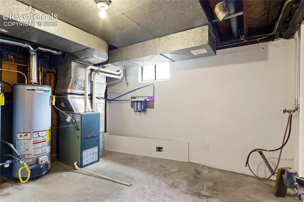 Image 33 of 36: Utility room featuring a water heater, furnace, and exposed overhead ductwo