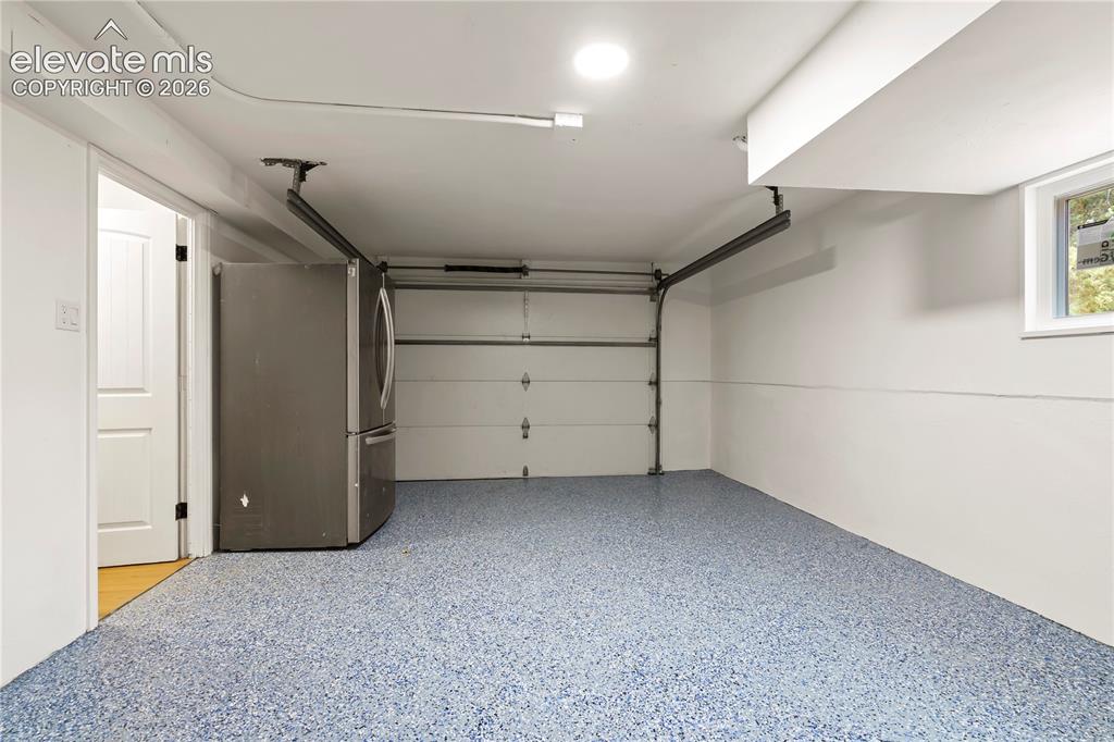 Image 35 of 36: Spacious garage with an epoxy chip floor coating, overhead garage door, rec