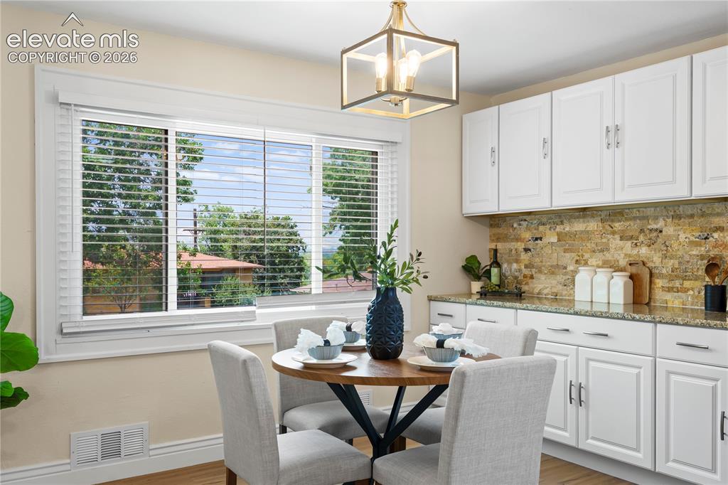 Image 4 of 36: Dining area featuring a window with white blinds, white upper and lower cab