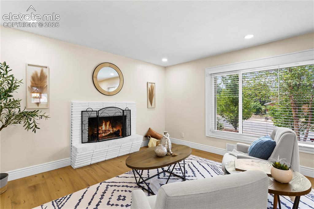 Image 6 of 36: Living area featuring a white brick fireplace with a metal screen
