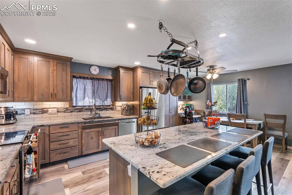 Image 10 of 50: Kitchen featuring light stone countertops, light wood-type flooring, decora