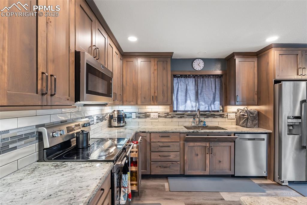 Image 11 of 50: Kitchen featuring light stone countertops, stainless steel appliances, deco