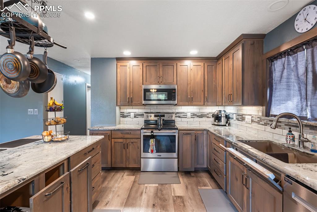 Image 13 of 50: Kitchen with appliances with stainless steel finishes, light stone countert