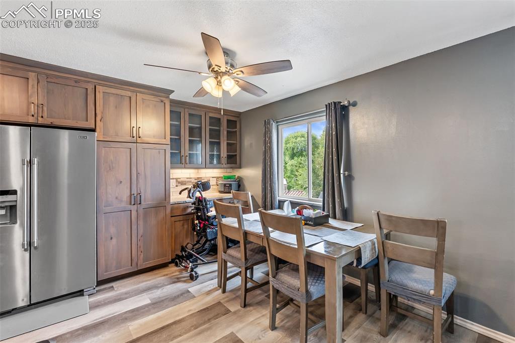 Image 14 of 50: Dining area with light wood finished floors and ceiling fan