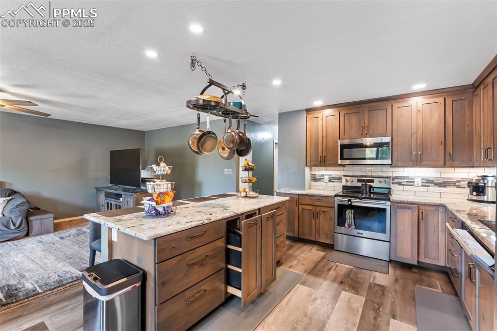 Image 15 of 50: Kitchen featuring decorative backsplash, open floor plan, light stone count