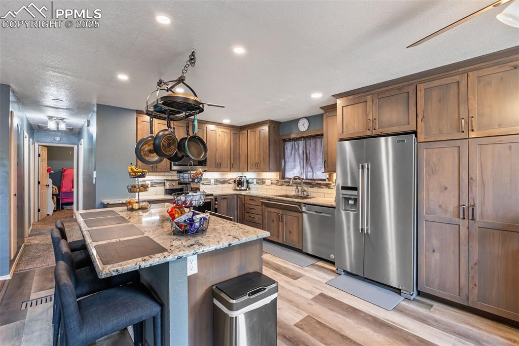Image 16 of 50: Kitchen with stainless steel appliances, backsplash, light wood-style floor