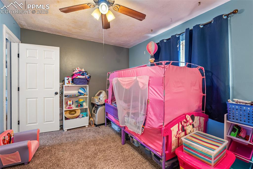 Image 24 of 50: Bedroom featuring carpet, a textured ceiling, and ceiling fan