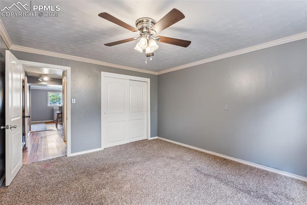 Image 27 of 50: Unfurnished bedroom with crown molding, a closet, carpet floors, and ceilin