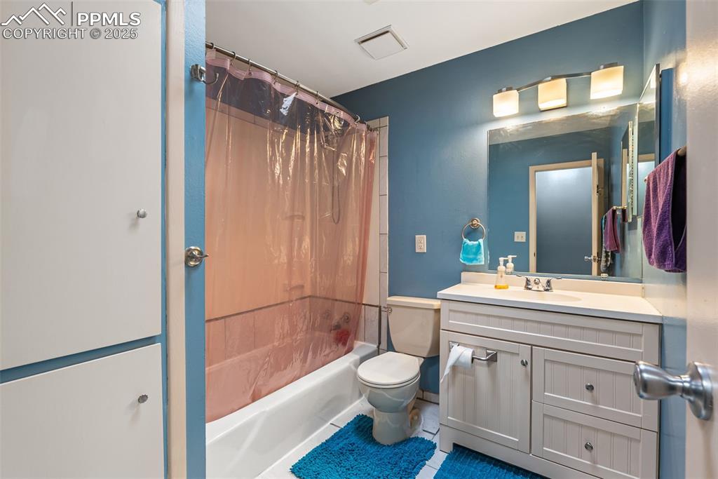 Image 28 of 50: Bathroom with shower / bathtub combination with curtain, vanity, and tile p