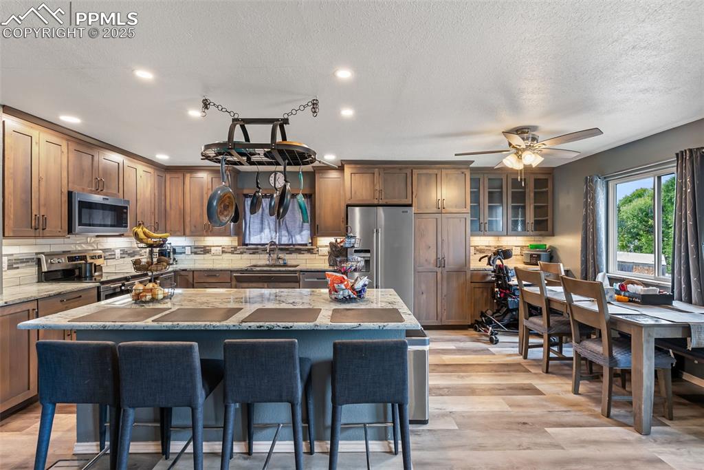 Image 3 of 50: Kitchen with decorative backsplash, a kitchen bar, stainless steel applianc