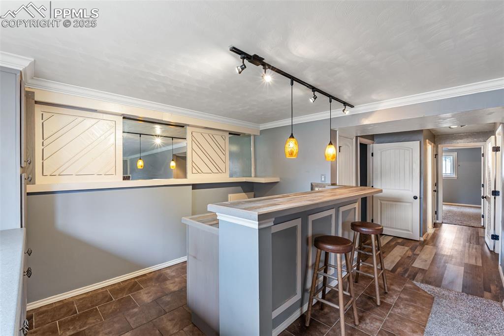 Image 33 of 50: Indoor dry bar featuring ornamental molding, track lighting, pendant lighti