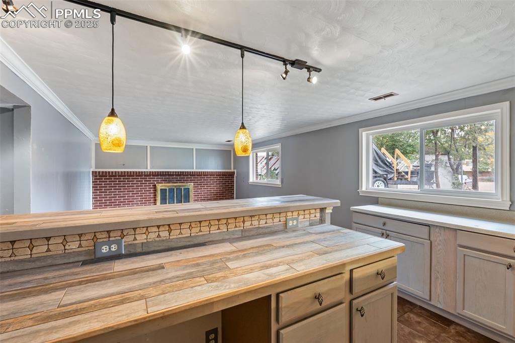 Image 36 of 50: Kitchen with track lighting, pendant lighting, crown molding, and tile coun