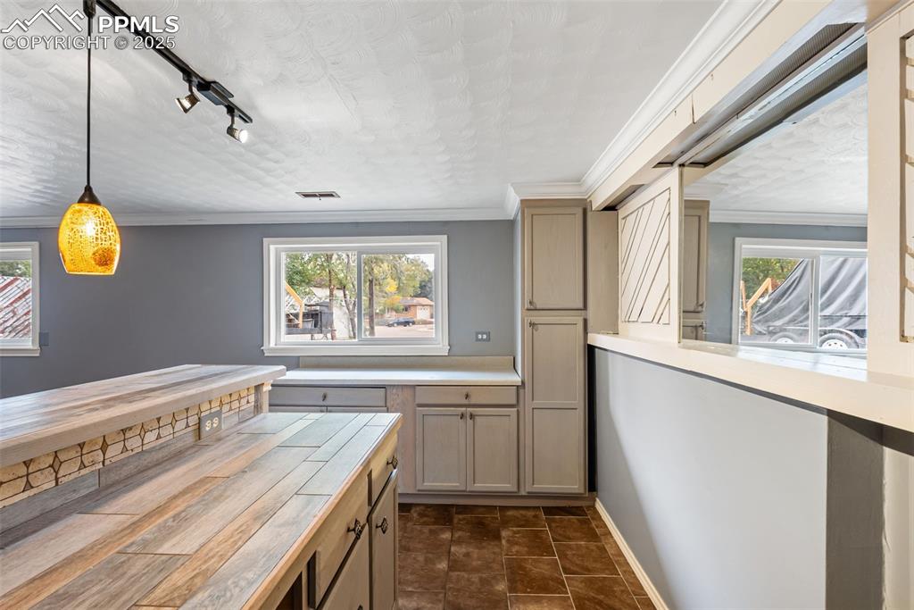Image 37 of 50: Kitchen featuring decorative light fixtures, crown molding, butcher block c