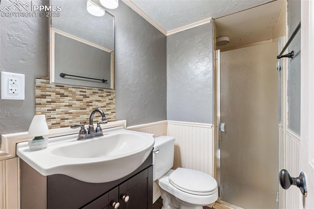 Image 39 of 50: Bathroom with a textured wall, vanity, a stall shower, crown molding, and t