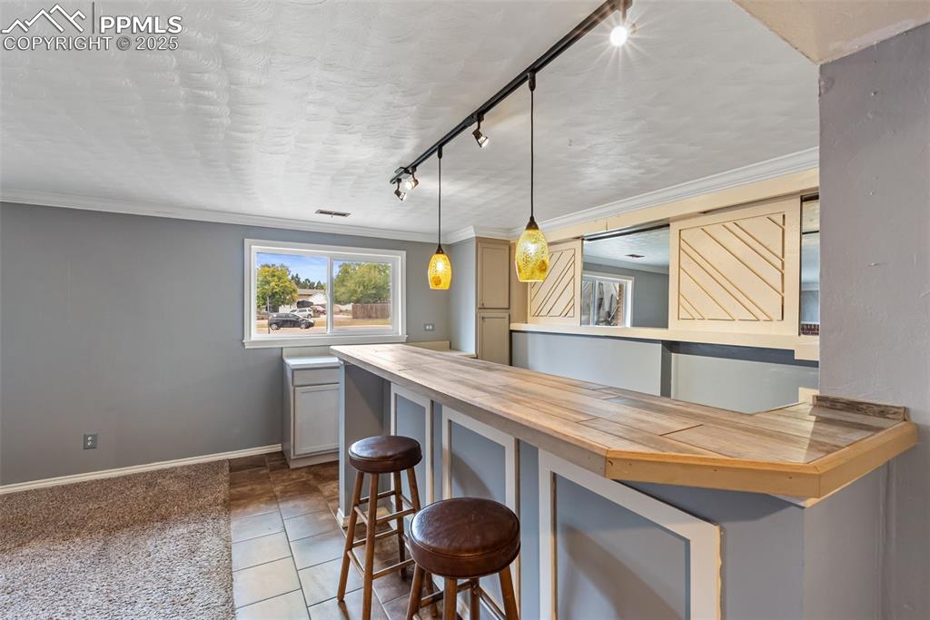 Image 4 of 50: Kitchen featuring a kitchen breakfast bar, track lighting, crown molding, b