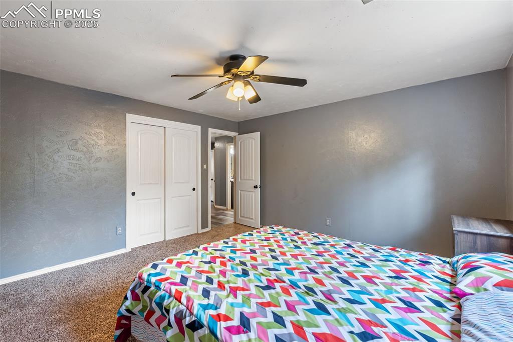 Image 41 of 50: Bedroom featuring carpet floors, a ceiling fan, a closet, and a textured wa