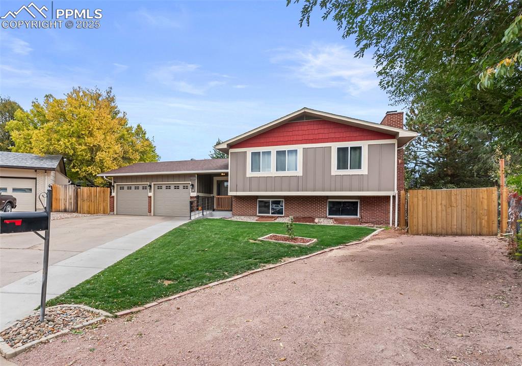 Image 44 of 50: Split level home with concrete driveway, a garage, a chimney, and brick sid