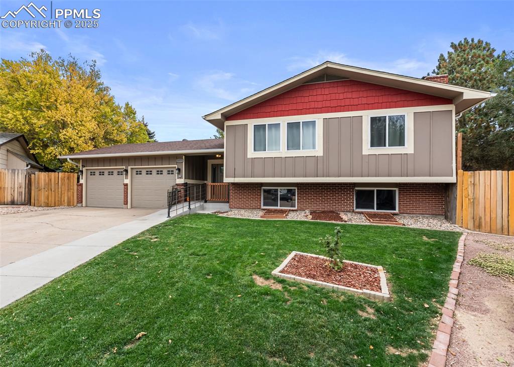 Image 45 of 50: Split level home featuring board and batten siding, a garage, and concrete
