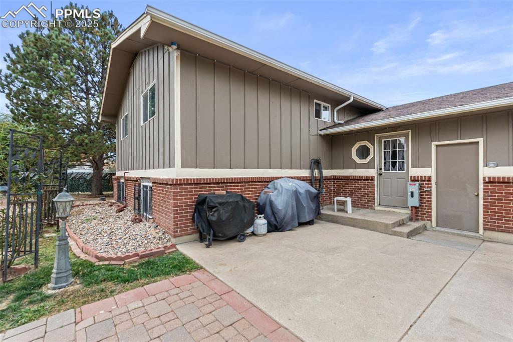 Image 46 of 50: Back of house featuring board and batten siding, brick siding, and a patio