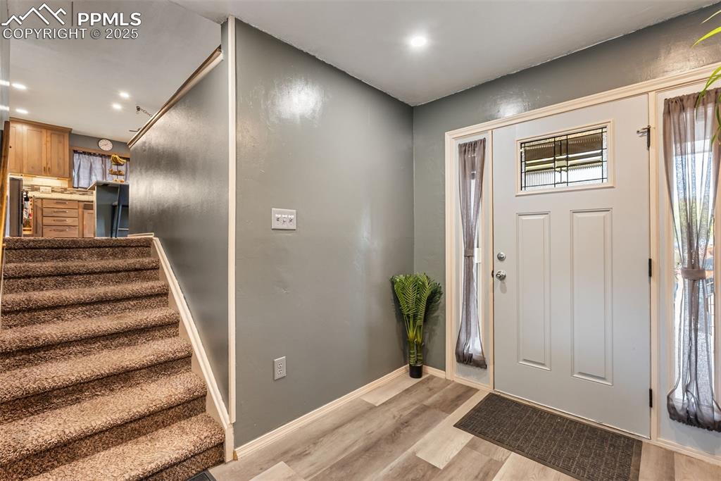 Image 9 of 50: Foyer entrance with light wood finished floors, stairway, and recessed ligh