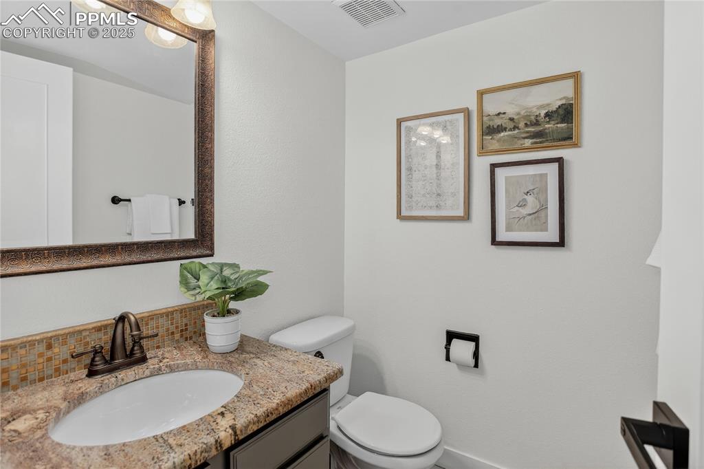 Image 24 of 47: Stylish powder bath with granite, lighting and handsome mirror