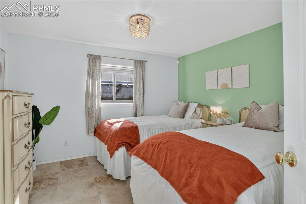 Image 34 of 47: Large lower level bedroom with travertine flooring, updated lighting, and a