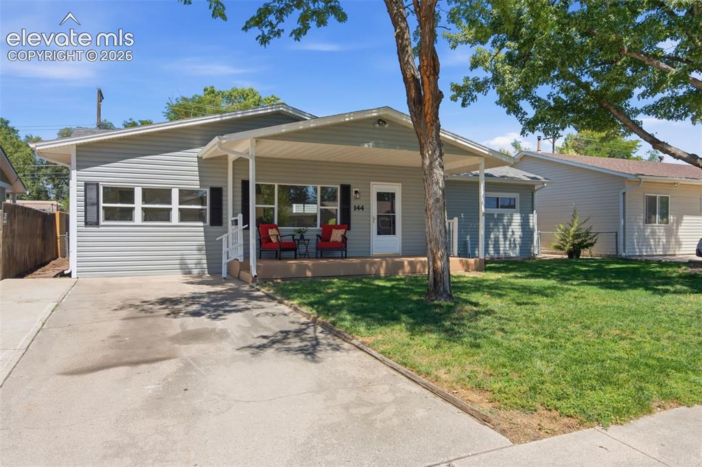 Caption: Light gray siding exterior with a covered porch, white railing, and a concrete driveway