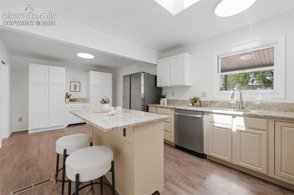 Image 10 of 34: Kitchen featuring a center island, light-toned countertops, wood-finish flo