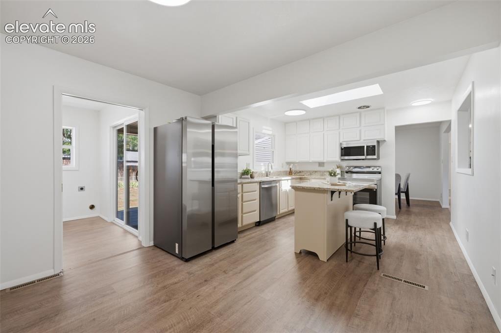 Image 14 of 34: Kitchen with white cabinetry, stainless steel appliances, a central island,