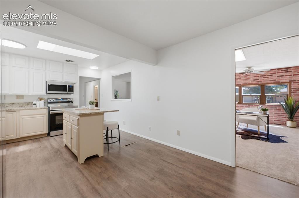 Image 16 of 34: Kitchen featuring white upper cabinetry, stainless steel appliances, light-