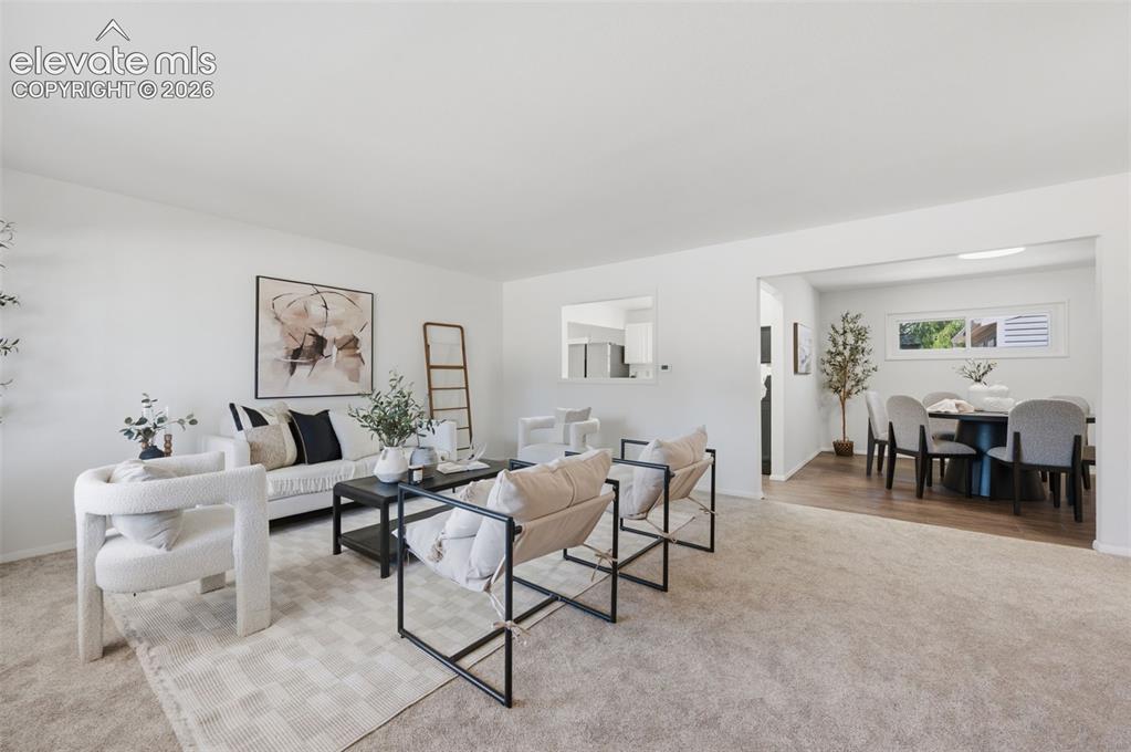 Image 3 of 34: Spacious living area featuring neutral carpeting and white wall finishes