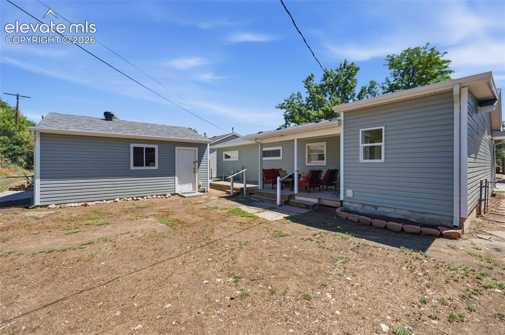 Image 30 of 34: Expansive backyard featuring a covered patio, multiple windows, light-toned