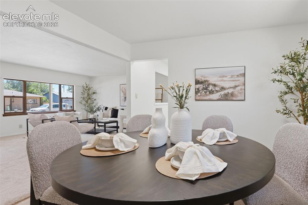 Image 9 of 34: Dining area with a dark round table and light-colored walls