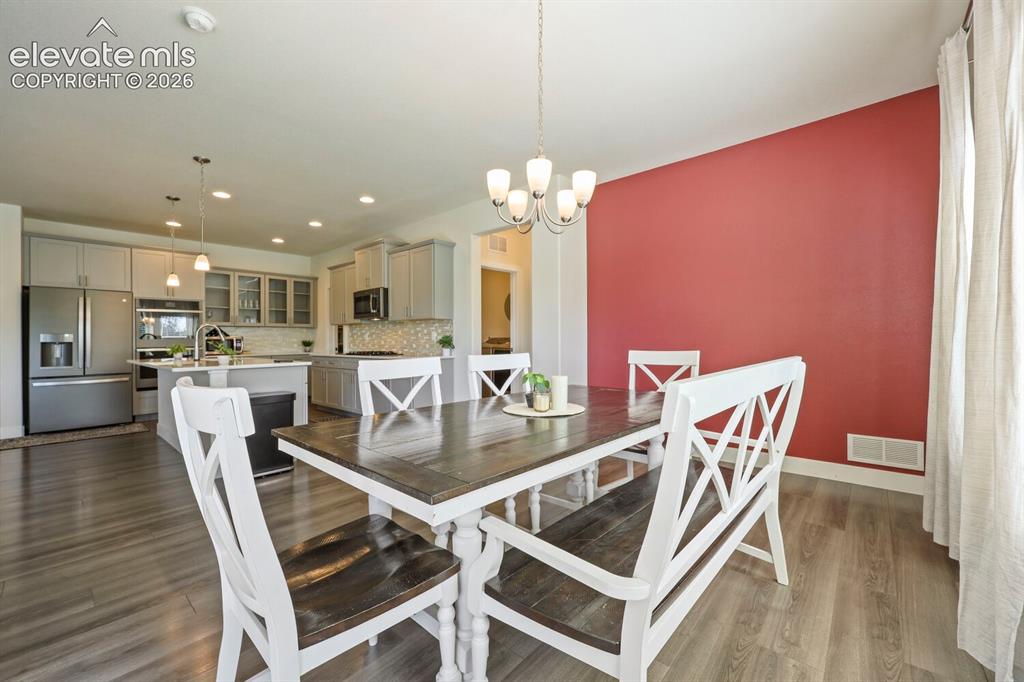 Image 12 of 45: Open-concept dining area featuring wood-finish flooring, a contemporary cha