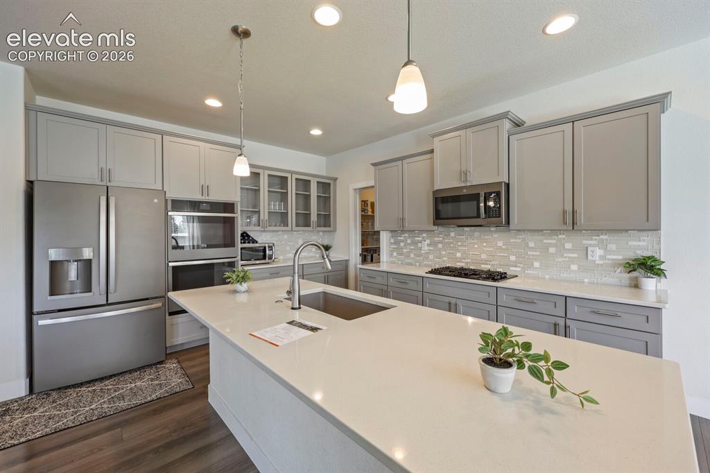 Image 14 of 45: Kitchen featuring an expansive island with a built-in sink, stone counterto