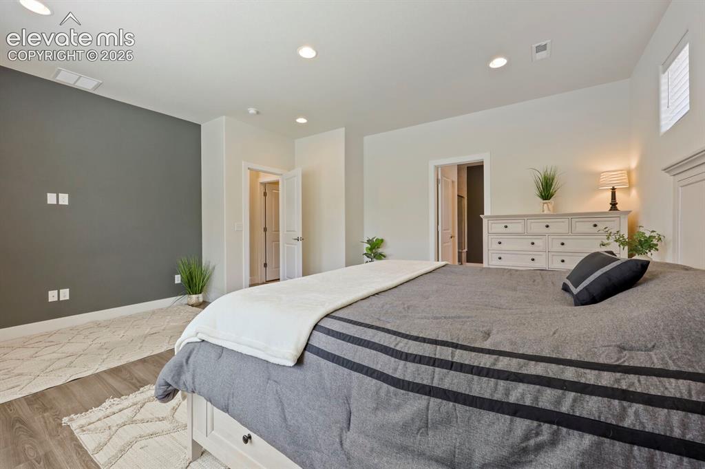 Image 19 of 45: Spacious bedroom featuring recessed lighting, a two-tone paint scheme, wood