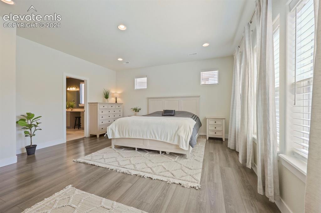 Image 20 of 45: Spacious bedroom featuring wood-finish flooring, recessed lighting, multipl