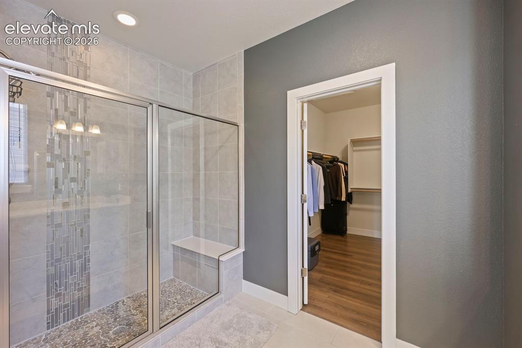 Image 22 of 45: Custom walk-in shower with clear glass enclosure, a mosaic tile accent, bui