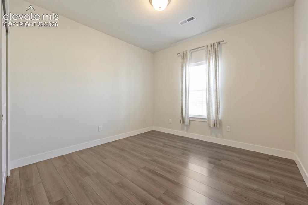 Image 31 of 45: Room featuring wood-finish flooring, a window with horizontal blinds and dr