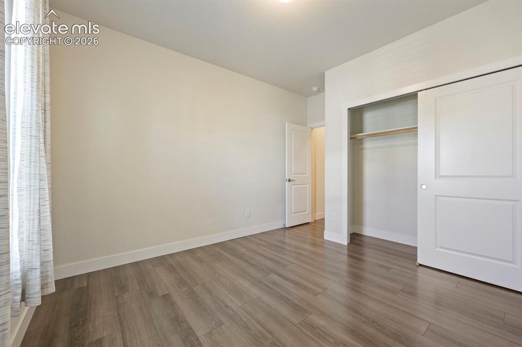 Image 32 of 45: Spacious room with wood-finish flooring, light-toned walls, and a large win