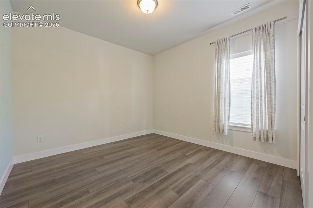 Image 33 of 45: Room featuring wood-finish flooring, white baseboards, a window with blinds