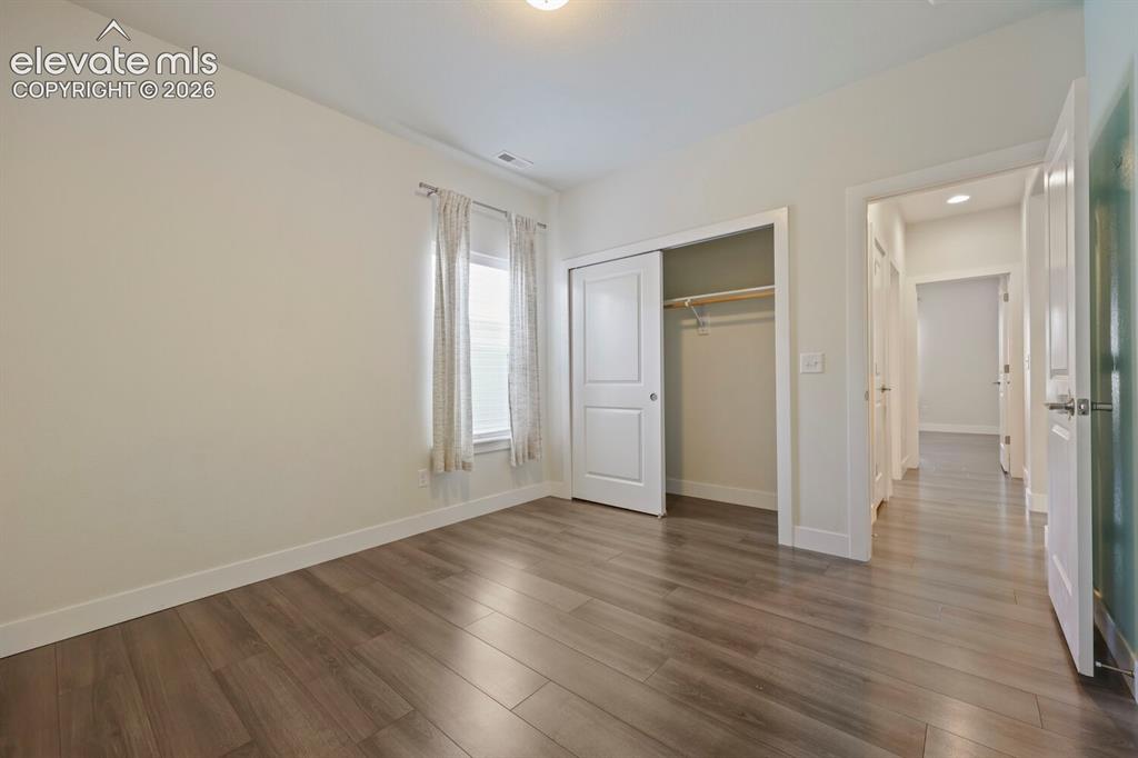 Image 35 of 45: Bedroom featuring wood-finish flooring, a double window with blinds, and a 
