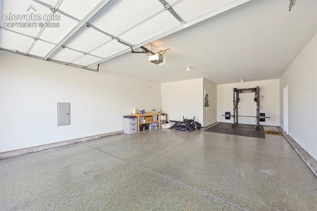 Image 36 of 45: Spacious garage featuring an overhead door, smooth concrete flooring with a