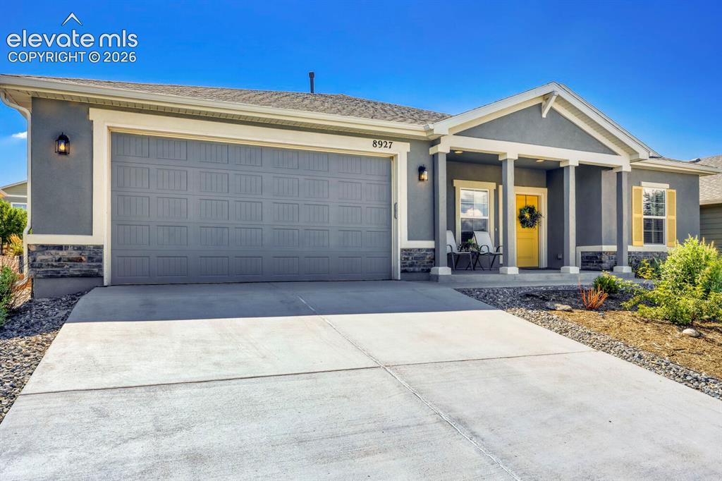 Image 4 of 45: Contemporary stucco exterior with a covered porch entry, stone veneer accen