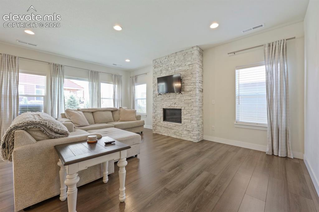 Image 8 of 45: Spacious living area featuring a stacked-stone-clad fireplace with built-in