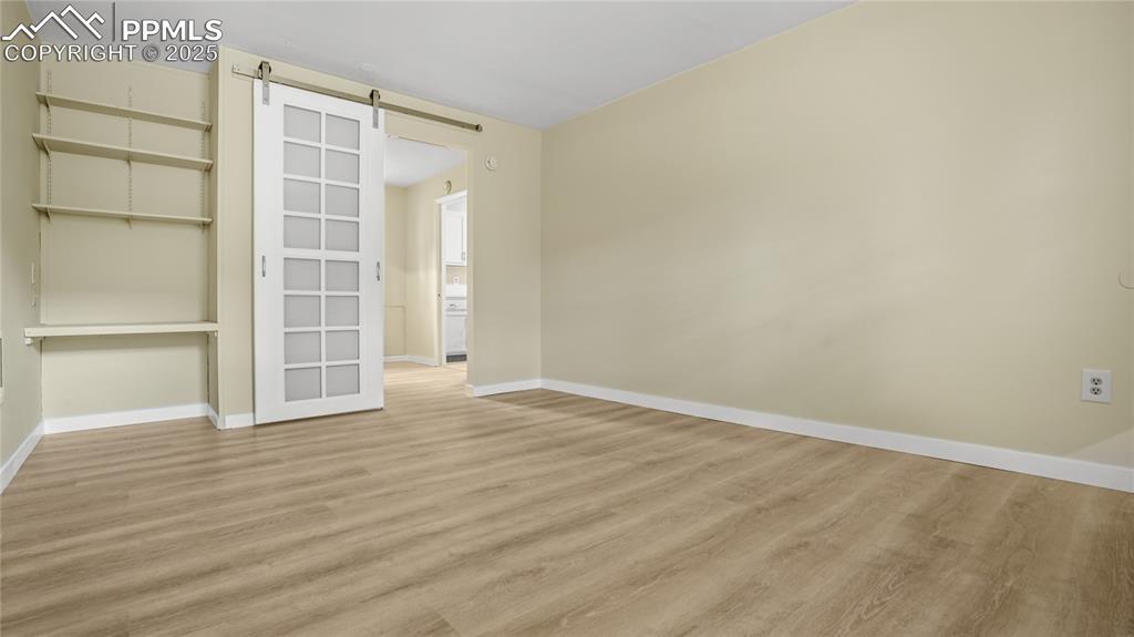 Image 11 of 25: Unfurnished room with a barn door and light wood-type flooring