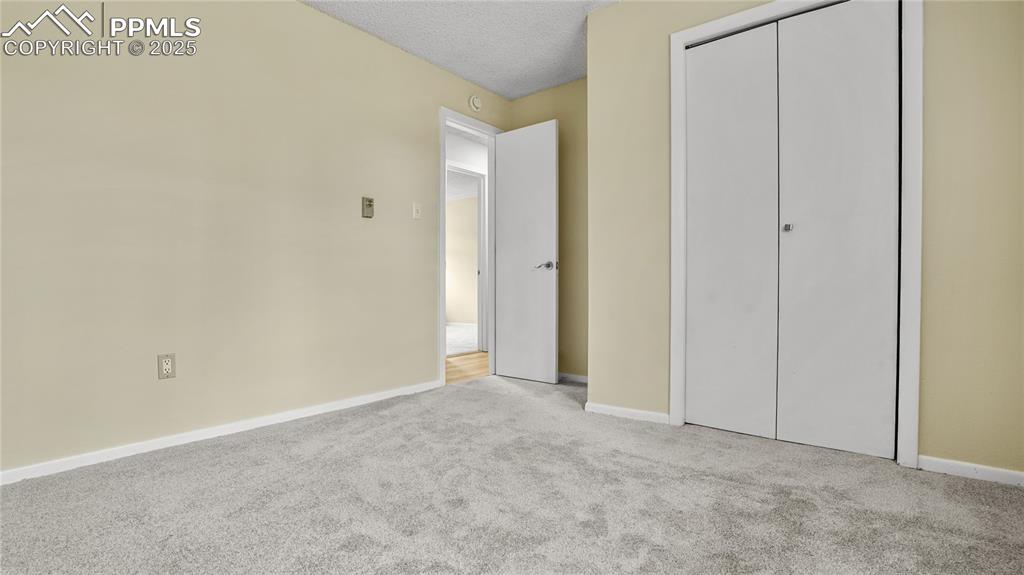 Image 13 of 25: Unfurnished bedroom featuring carpet floors, a textured ceiling, and a clos