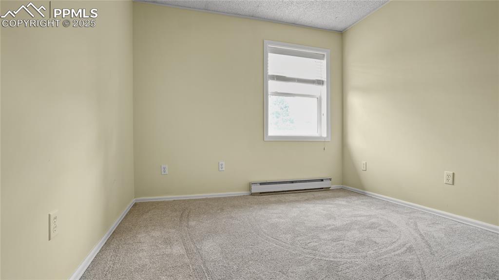 Image 16 of 25: Carpeted spare room featuring a baseboard heating unit and a textured ceili