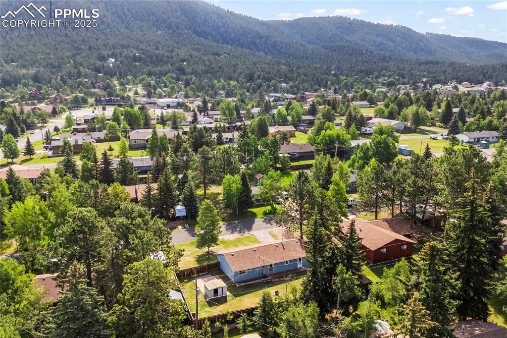 Image 23 of 25: Aerial view of residential area with a mountain backdrop and a heavily wood